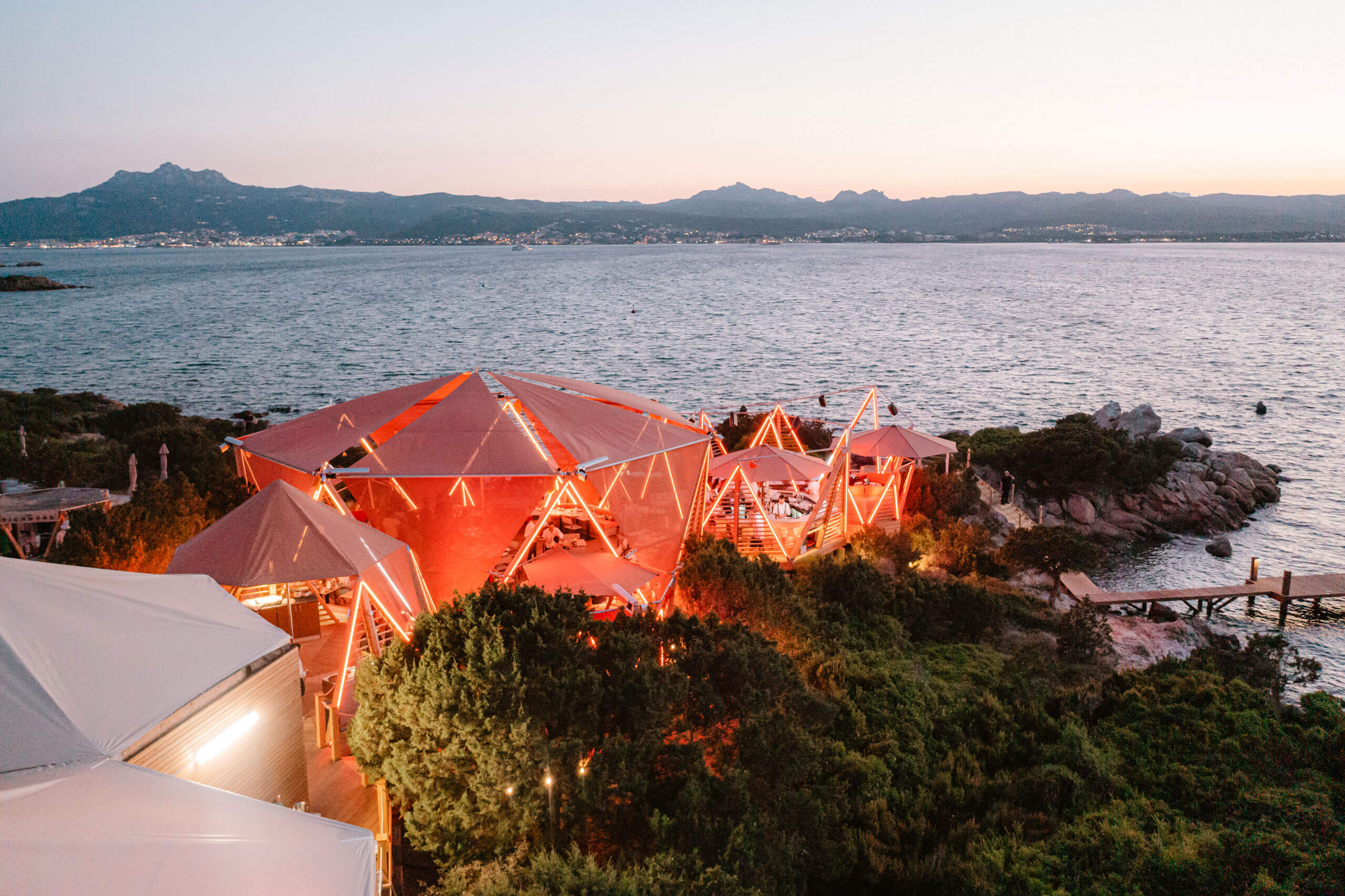 A tent with lights on the side of a body of water