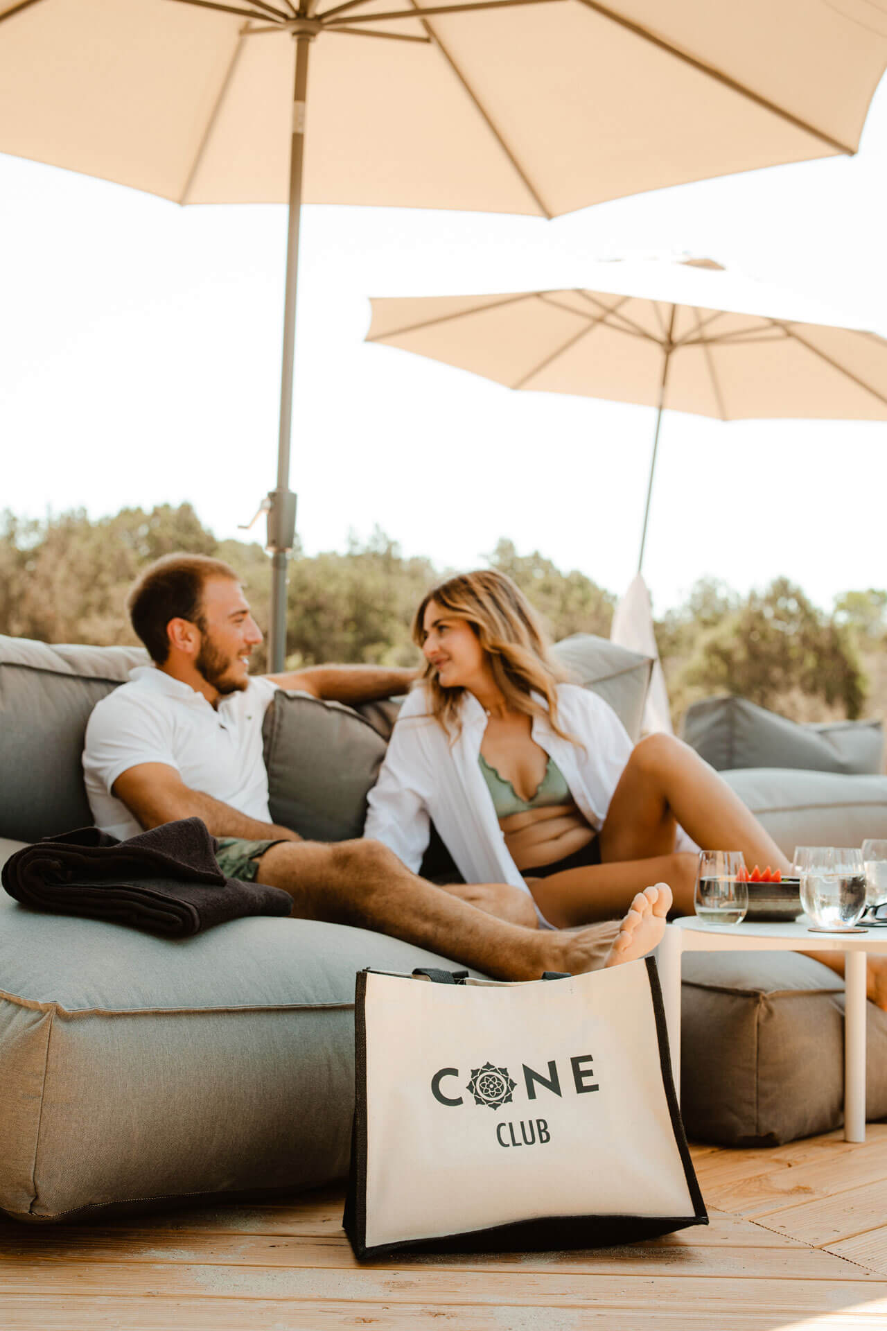 A man and woman sitting on a couch at Cone Club, enjoying their perfect day and night. ReservationsD