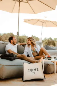 A man and woman sitting on a couch at Cone Club, enjoying a reservation date with Felicity. Book your perfect day and night to remember at Cone Club.