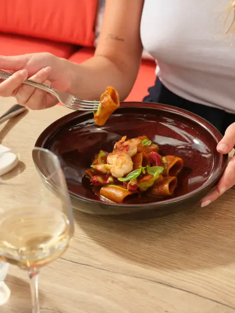 Enjoying a delicious pasta dish with shrimp and a glass of white wine.