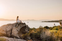 Una donna seduta su una roccia che gode della vista pittoresca dell'acqua