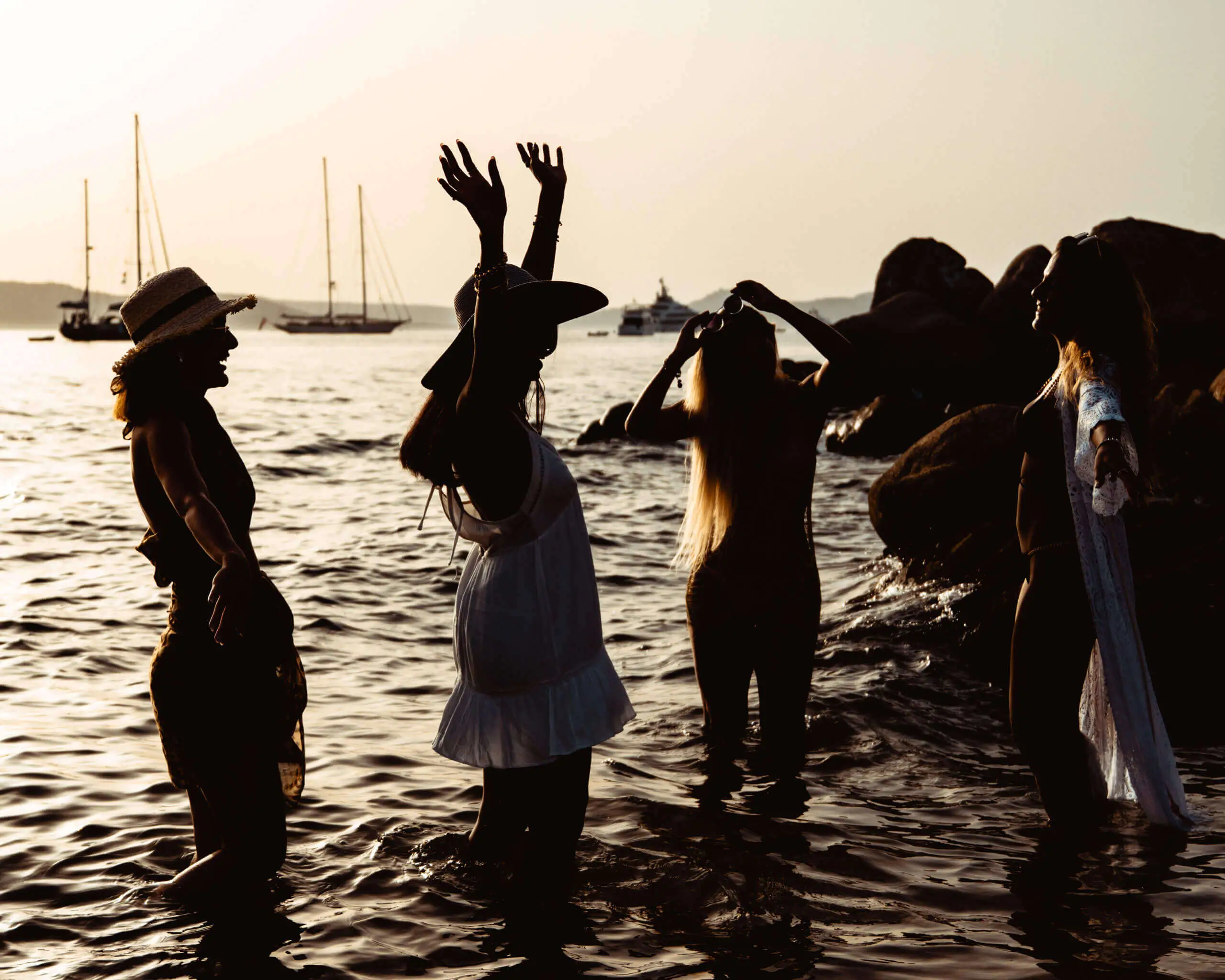 Silhouetted women enjoying a sunset beach gathering by the sea for the 